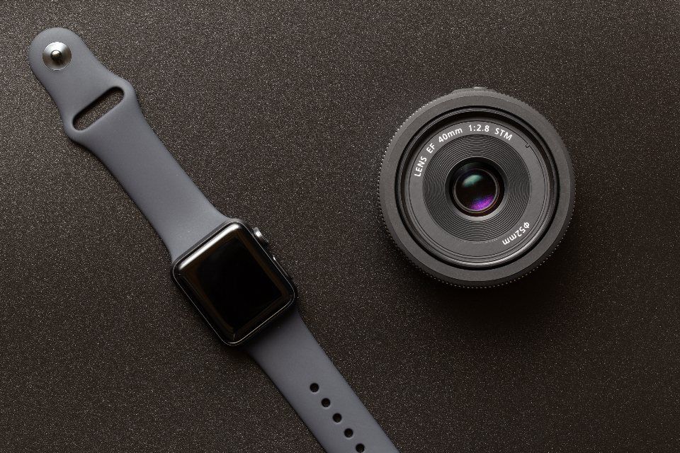 Apple Watch se šedým řemínkem na tmavém stole